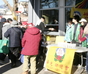 溫哥華華光功德會義工在日本公園派送熱食給街頭遊民，圖為遊民排隊領取熱食p1046-13-05