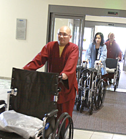 圖為法師及義工將輪椅推進醫院p1108-08-05