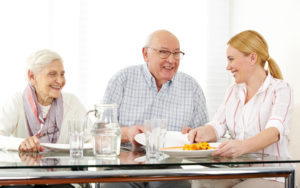 Happy family with senior couple eating lunch at table